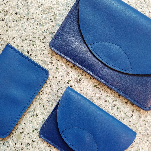 three blue wallets made of recycled leather in a flat lay composition with a speckled background
