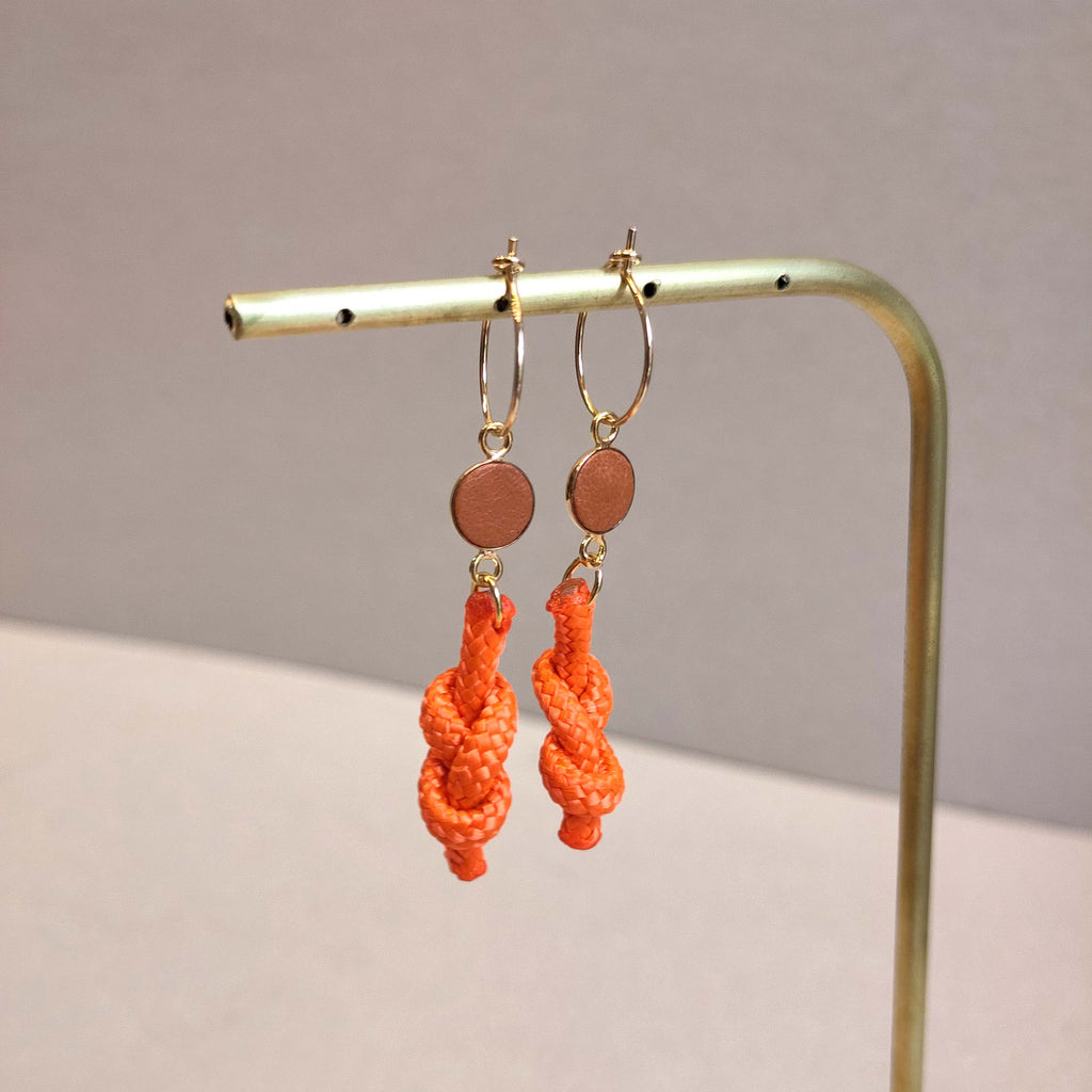 golden earrings with a round orange piece of eco leather and recycled orange rope. Made by Anna Treurniet